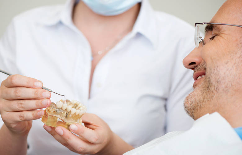 οδοντίατρος εξηγεί σε ασθενή γ ια την τεχνητή οδοντοστοιχία