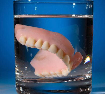 τεχνητή οδοντοστοιχία σε ποτήρι με νερό