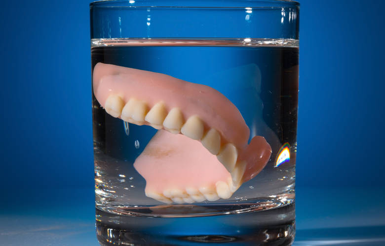 τεχνητή οδοντοστοιχία σε ποτήρι με νερό