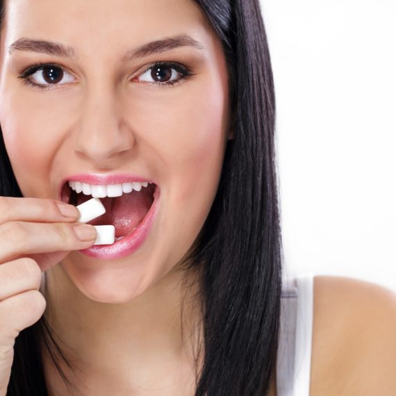Beautiful girl taking white chewing gum, smiling